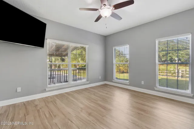 a view of an empty room with a window and wooden floor