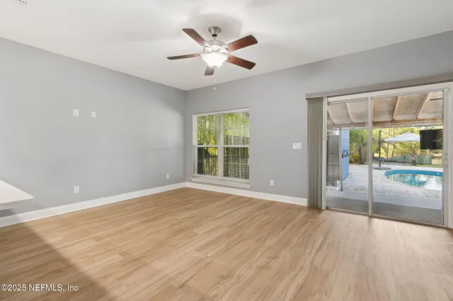 a view of an empty room with a window and wooden floor