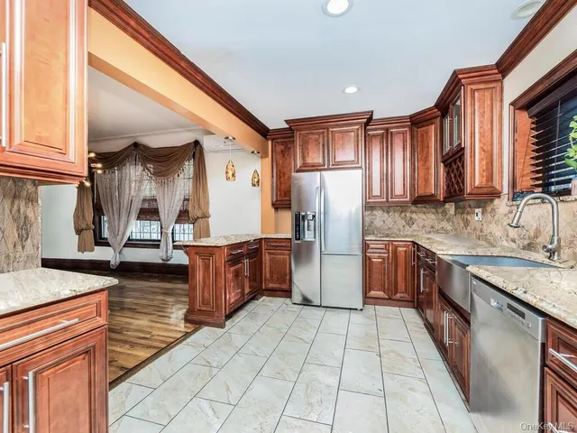a kitchen with stainless steel appliances granite countertop a refrigerator a stove and a sink