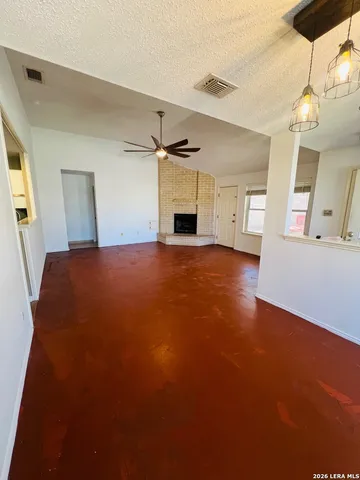 a view of an empty room with a fireplace and a window