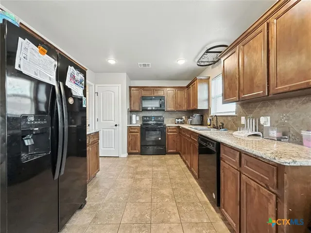 a large kitchen with stainless steel appliances granite countertop a refrigerator a sink a stove and oven