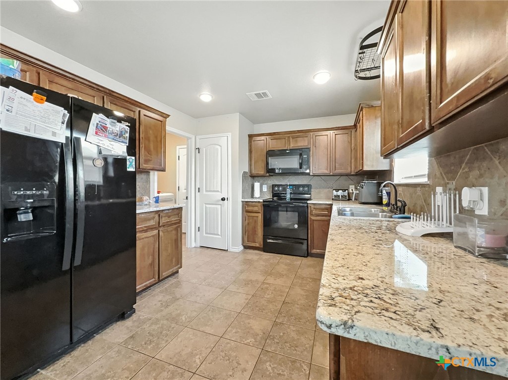 2701 Settlement Road Copperas Cove, TX 76522 - Photo 3 of 18 a kitchen with stainless steel appliances granite countertop a refrigerator a stove a sink and a microwave