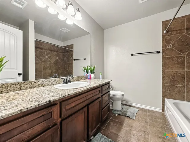 a bathroom with a granite countertop sink a toilet and shower