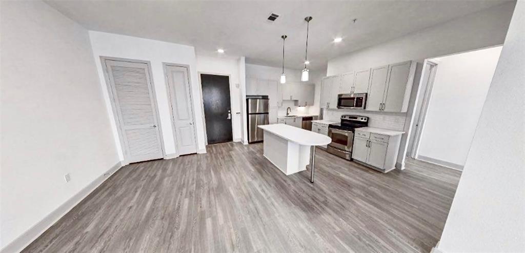 a living room with stainless steel appliances kitchen island hardwood floor and a view of kitchen