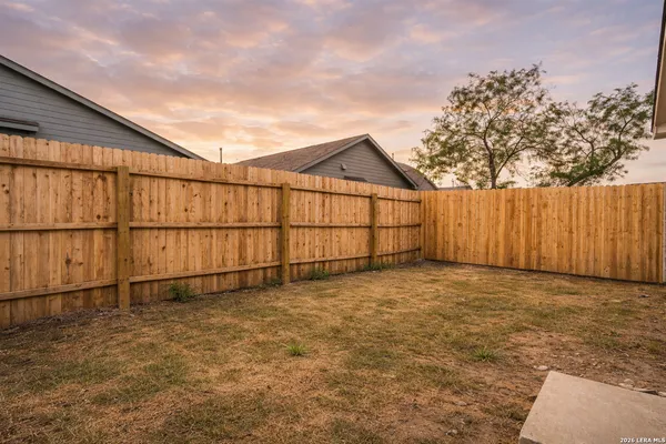 a view of backyard space with wooden fence