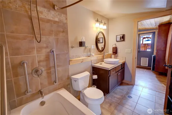 a bathroom with a tub sink mirror vanity and toilet