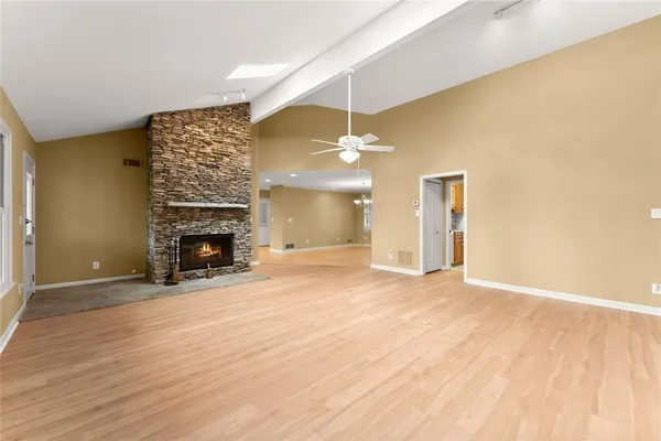 an empty room with wooden floor fireplace and windows