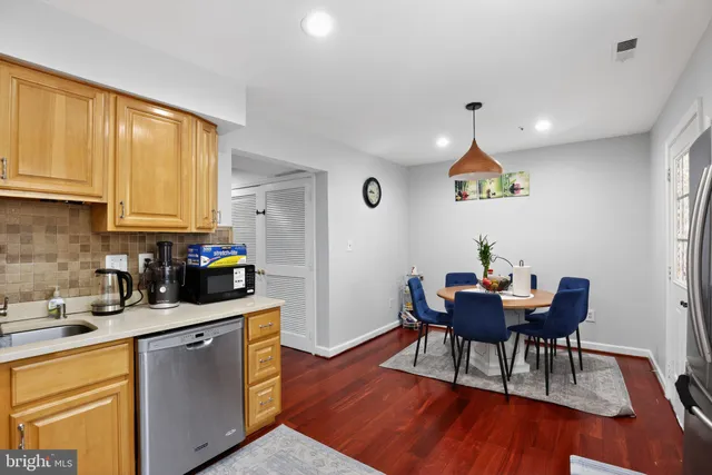 a kitchen with stainless steel appliances granite countertop wooden floors a dining table and chairs