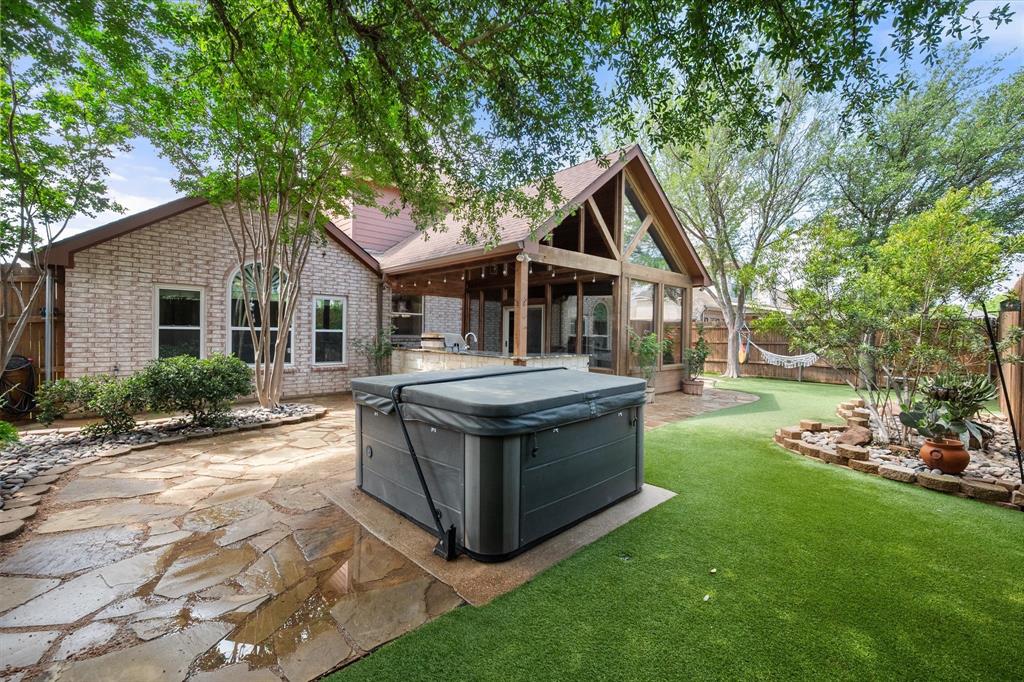 1305 Liverpool Lane Mansfield, TX 76063 - Photo 35 of 40 The property features a backyard with a hot tub, a stone patio, and a well-maintained lawn