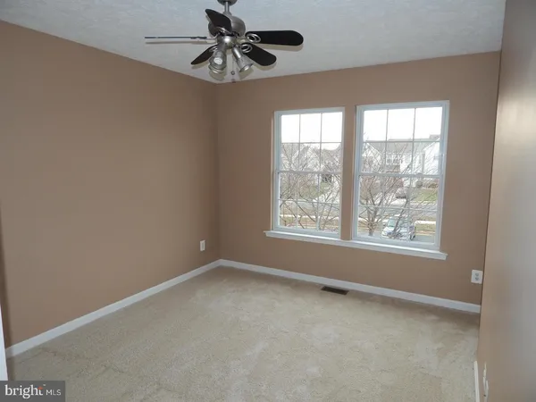 an empty room with a window and a fan