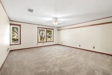 an empty room with windows and chandelier fan