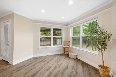 a view of an empty room with a window and wooden floor