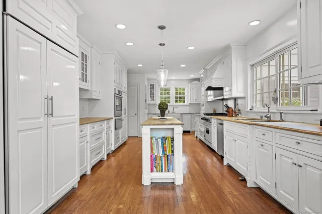 a large kitchen with kitchen island wooden floors white cabinets and stainless steel appliances