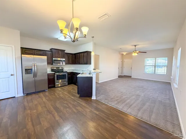 a kitchen with granite countertop a stove a sink dishwasher a refrigerator and a fireplace