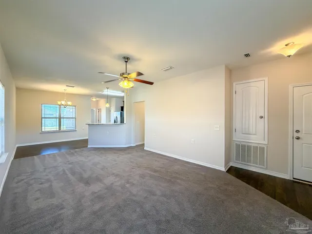 an empty room with windows and chandelier fan