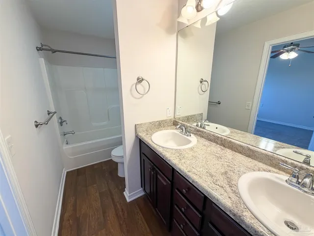 a bathroom with a granite countertop sink a toilet a mirror and shower
