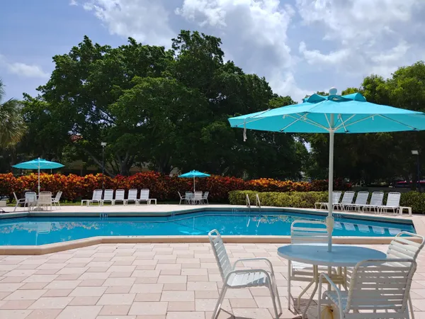 a view of a table and chairs under an umbrella in front of house
