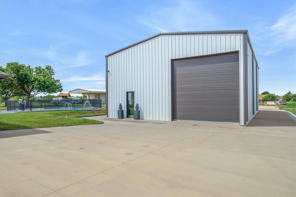 9346 Homestead Lane Forney, TX 75126 - Photo 24 of 39 60 X 40 shop/barndo with two walk through doors, two 16 foot bay roll-up doors, front and back with drive thru capacity -- extra concrete for moving trailers or heavy equipment in and out.