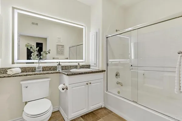 a bathroom with a granite countertop sink a toilet and shower