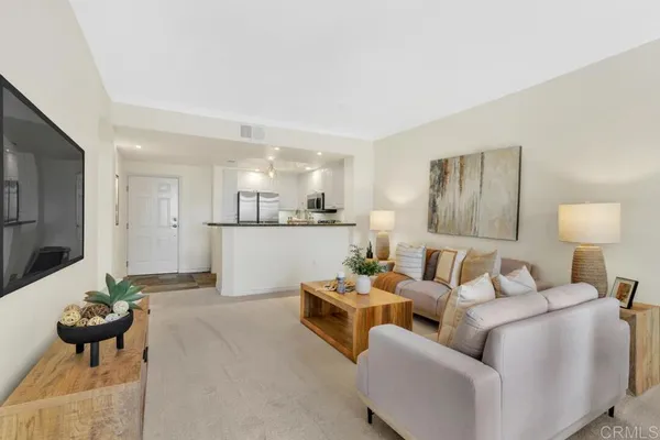 a living room with furniture white walls and a view of kitchen