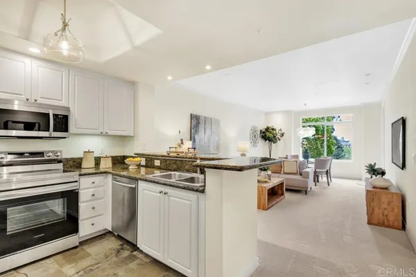 a kitchen with stainless steel appliances a stove a sink a microwave a dining table and chairs