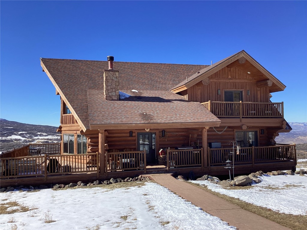 View of front of property with log exterior, a shingled roof, a chimney, board and batten siding, and a mountain view