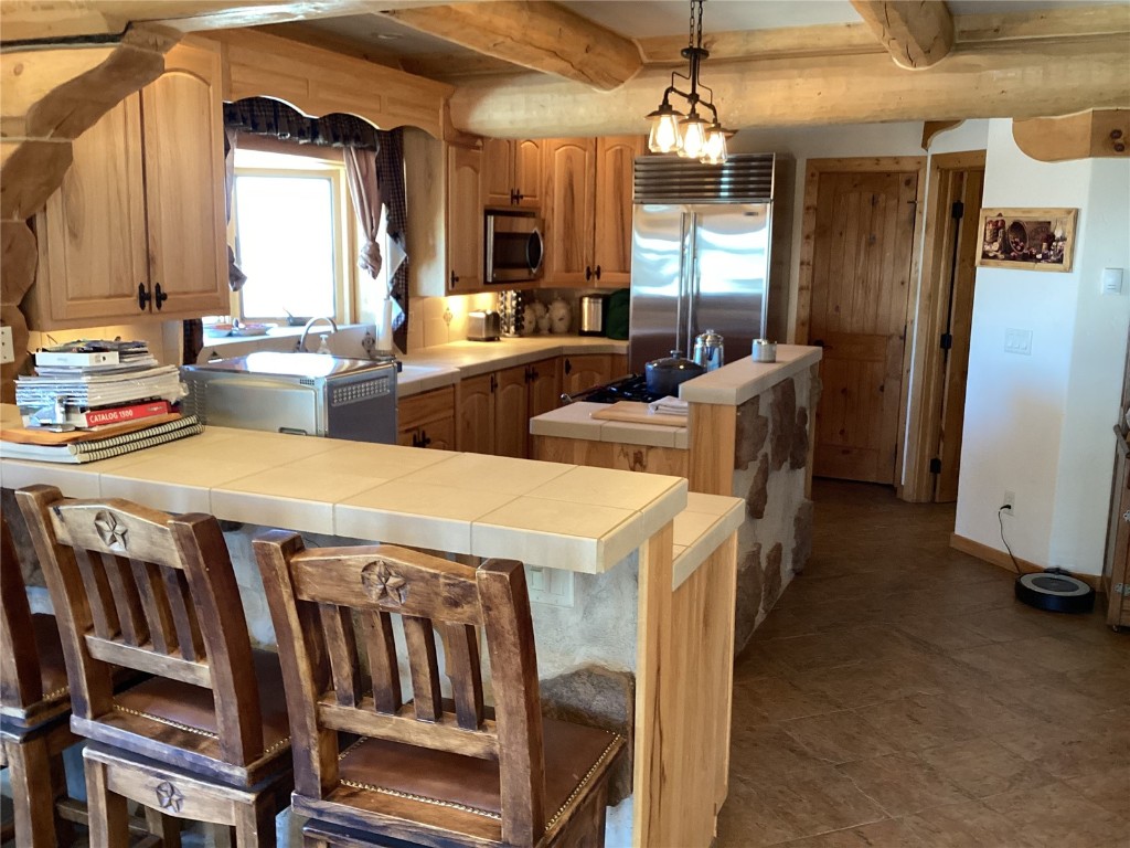 9073 54 7/10 Road Molina, CO 81646 - Photo 15 of 38 Kitchen with a kitchen island, a kitchen bar, stainless steel appliances, decorative light fixtures, and tile counters
