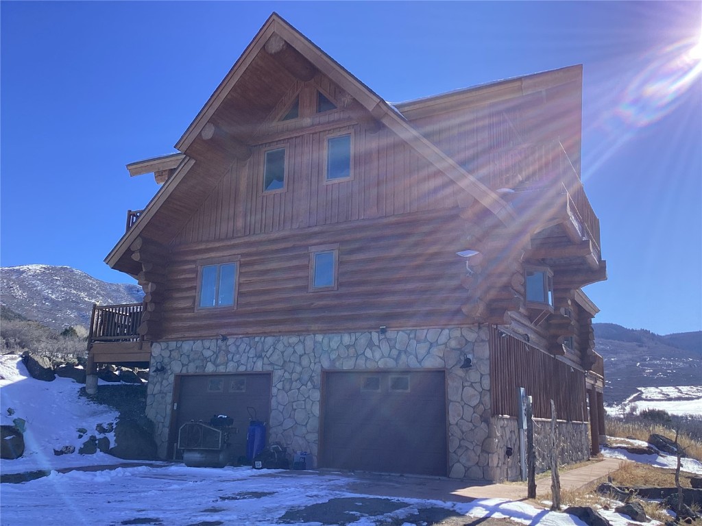 9073 54 7/10 Road Molina, CO 81646 - Photo 6 of 38 Snow covered property featuring log exterior, stone siding, a garage, and a deck with mountain view