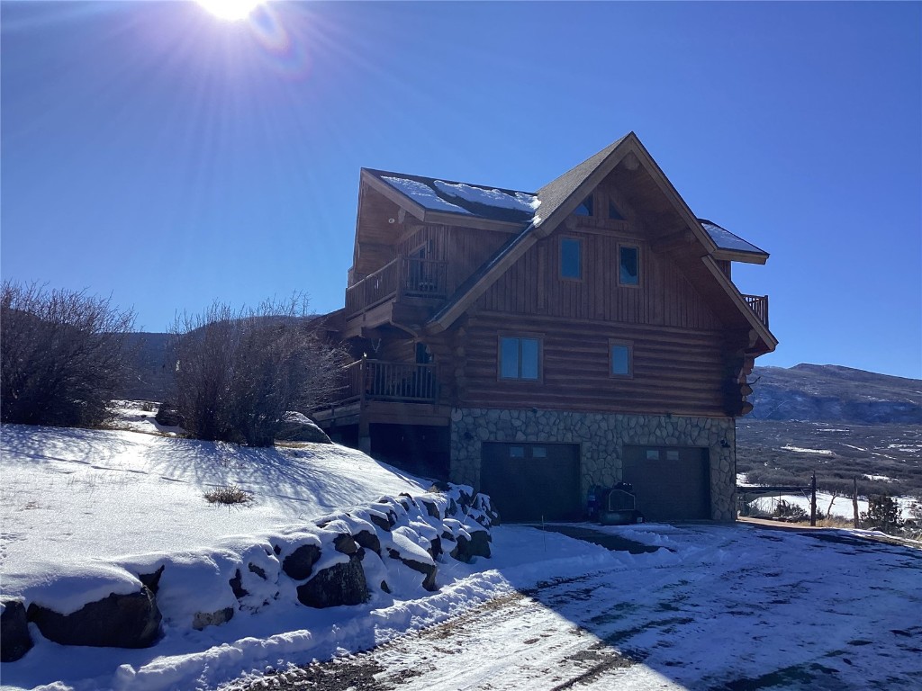 9073 54 7/10 Road Molina, CO 81646 - Photo 7 of 38 View of snowy exterior featuring log exterior, an attached garage, and stone siding