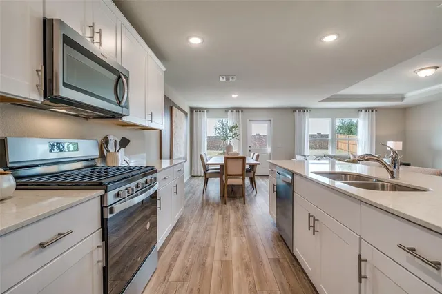 a kitchen with a table chairs a sink dishwasher stove and cabinets with wooden floor