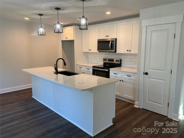 a kitchen with stainless steel appliances a sink a stove a microwave and wooden floor