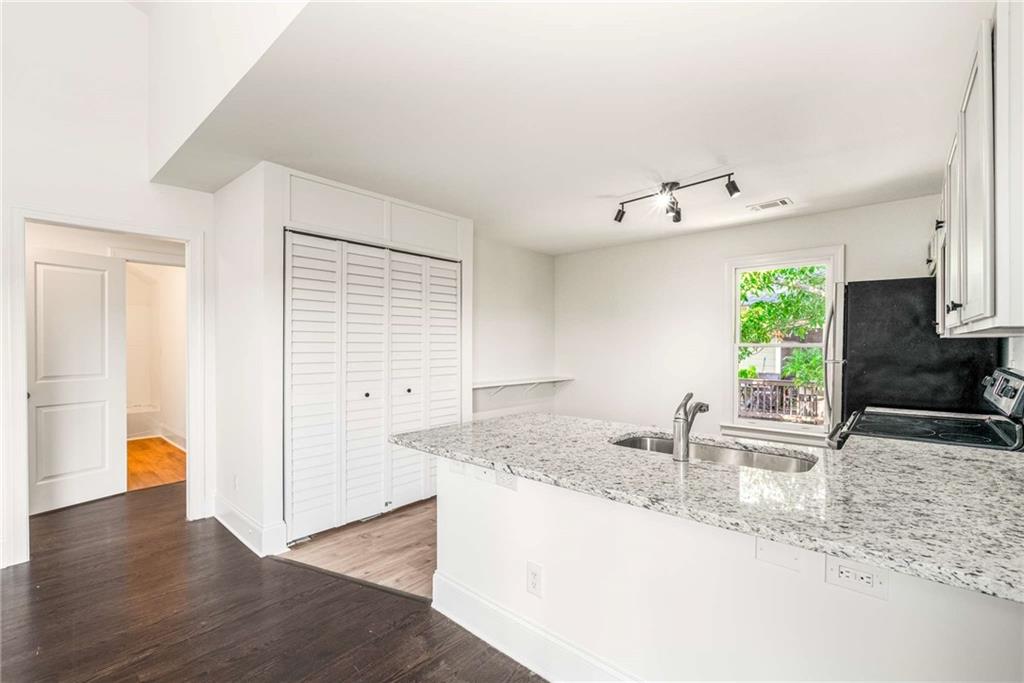 94 Lucy Street Southeast, Unit A Atlanta, GA 30312 - Photo 12 of 25 a kitchen with stainless steel appliances granite countertop a sink a stove and a wooden floors
