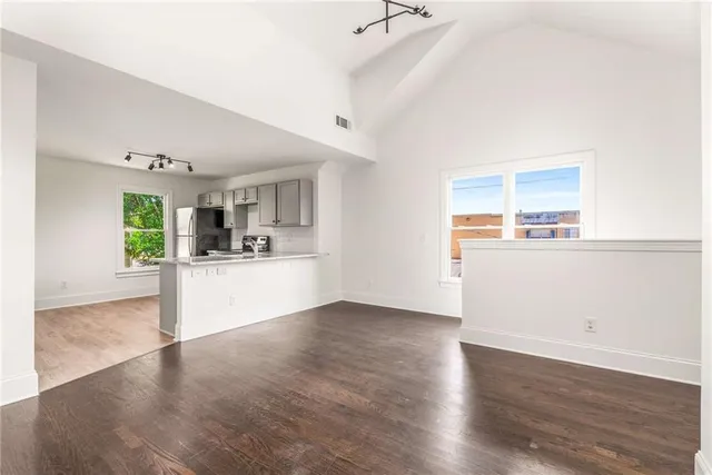 a view of a kitchen and an empty room with wooden floor