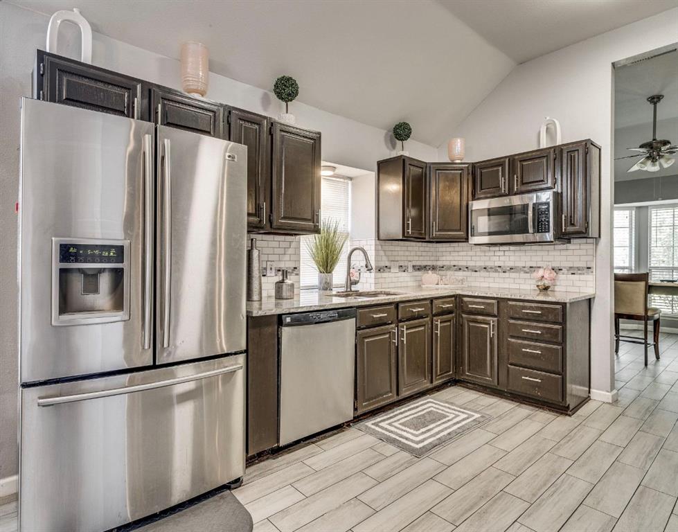 a kitchen with granite countertop stainless steel appliances a refrigerator sink and microwave