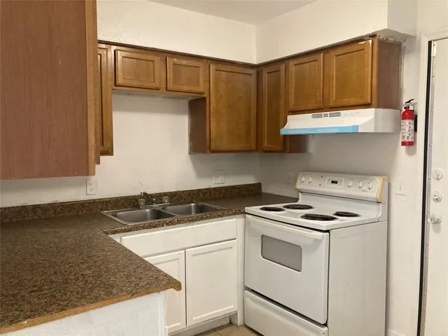 a kitchen with granite countertop a sink stove and cabinets