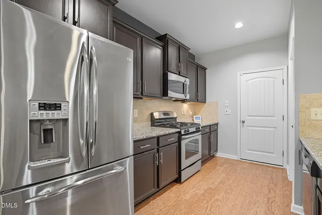 a kitchen with stainless steel appliances granite countertop a refrigerator and a stove