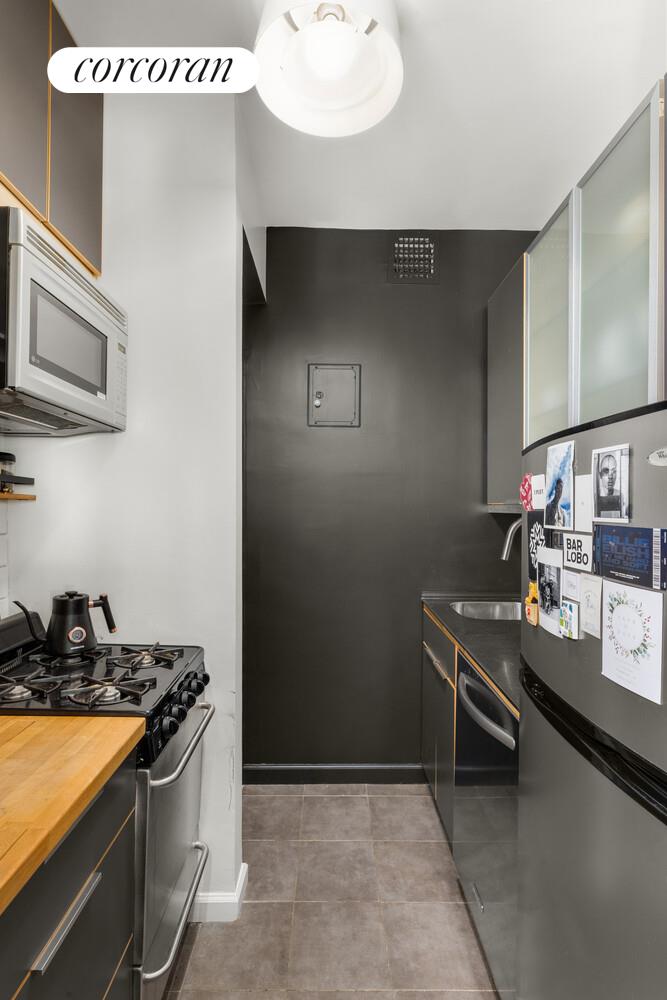207 East 21st Street, Unit 3B Manhattan, NY 10010 - Photo 3 of 6 a kitchen with stainless steel appliances a sink stove and cabinets