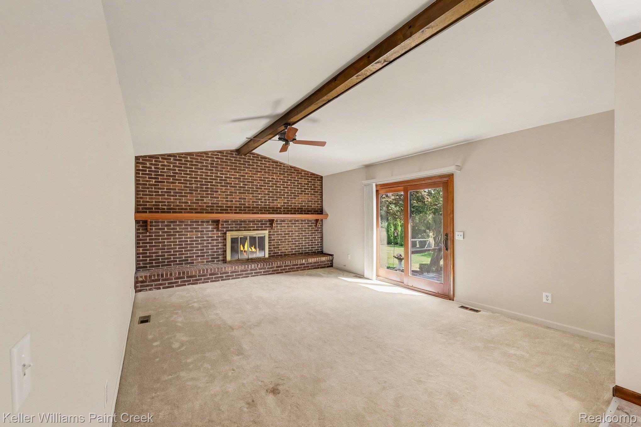 2717 Powderhorn Ridge Road Rochester, MI 48309 - Photo 8 of 48 Vaulted ceiling with exposed wood beam, brick fireplace with mantel, sliding glass door, and ceiling fan