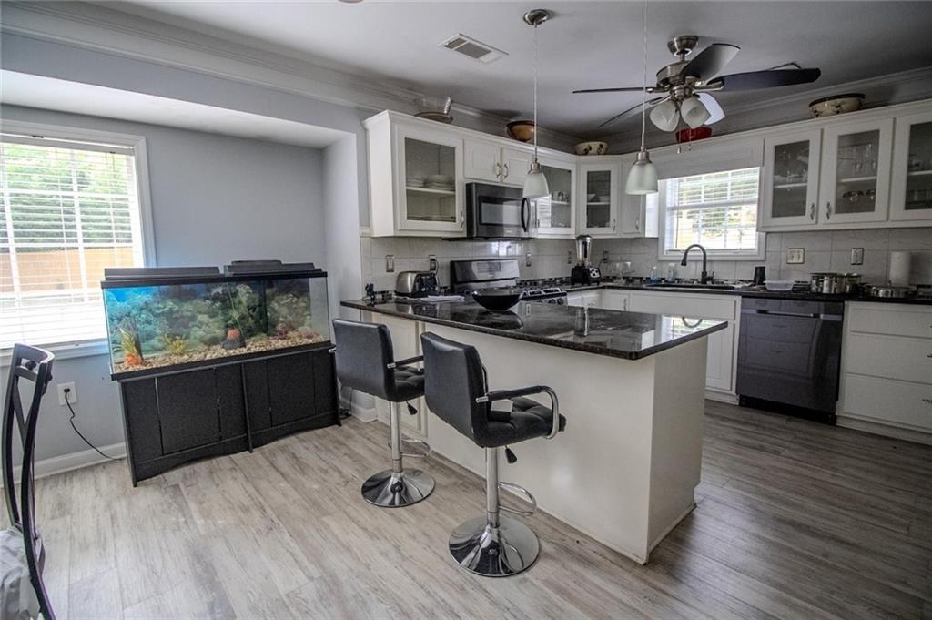 4184 Red Laurel Way Southwest Snellville, GA 30039 - Photo 4 of 35 a kitchen with stainless steel appliances granite countertop a stove a sink dishwasher a dining table and chairs with wooden floor