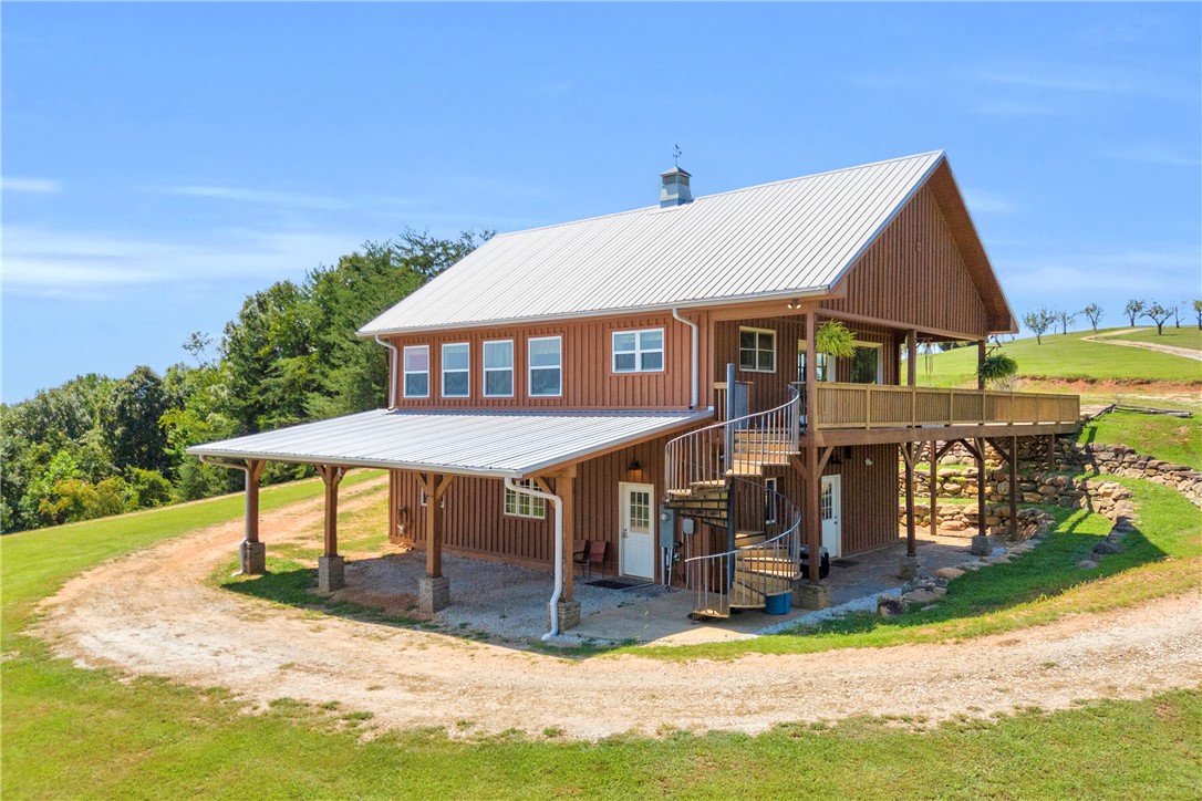 Metal roofing and rustic vertical siding define this two-story structure featuring an elevated wrap-around deck.
