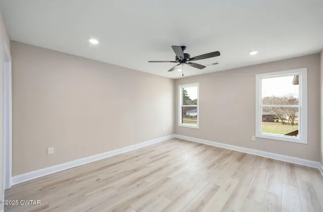 a view of an empty room with a window and wooden floor