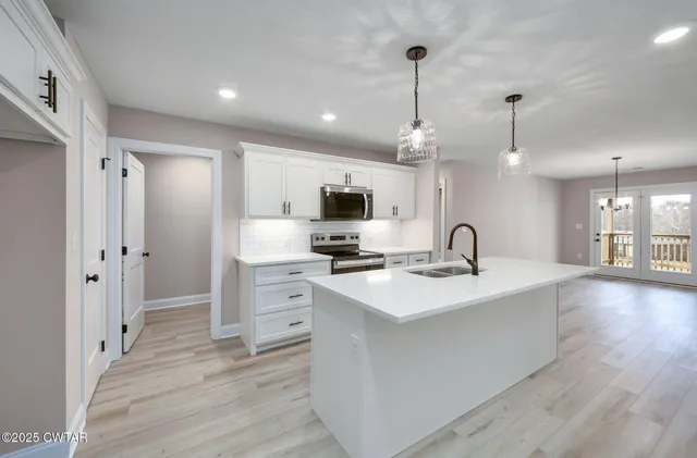 a large kitchen with stainless steel appliances a large counter top a stove a sink and a refrigerator