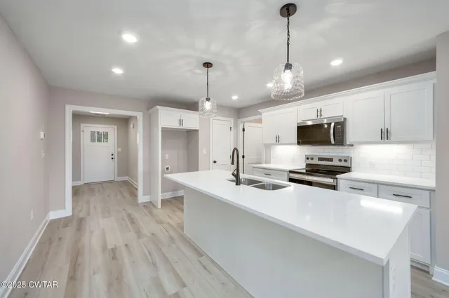 a kitchen with stainless steel appliances a sink stove and wooden floor