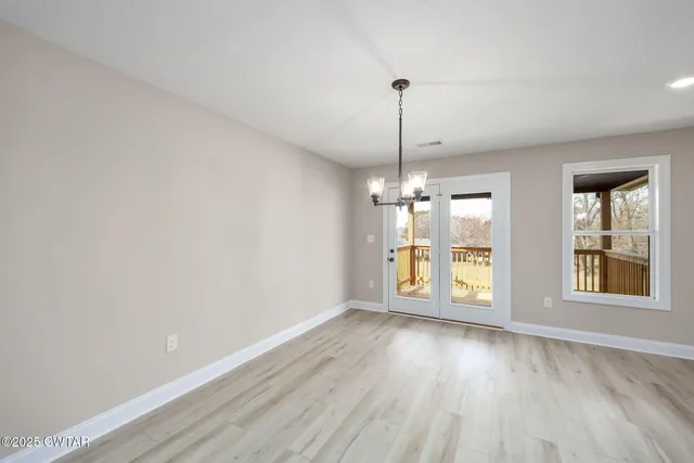 a view of an empty room with window and wooden floor