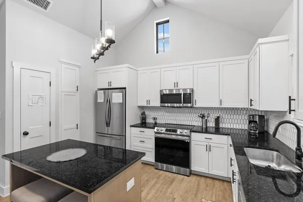 a kitchen with stainless steel appliances granite countertop a stove a refrigerator a sink a stove and white cabinets
