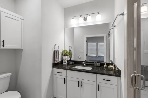 a bathroom with a granite countertop sink a toilet and mirror
