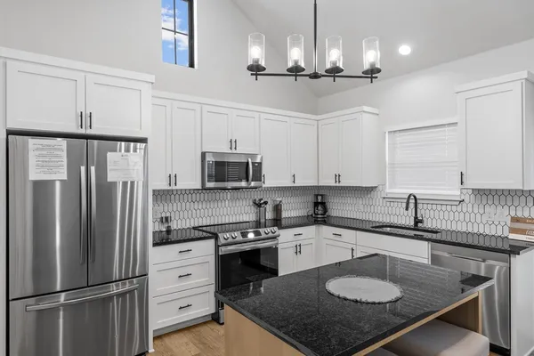 a kitchen with stainless steel appliances granite countertop a sink a stove a refrigerator cabinets and a center island