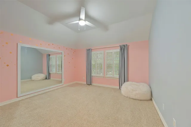 a view of an empty room with chandelier fan and bathroom