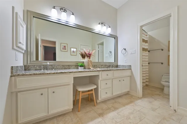 a bathroom with a granite countertop sink a toilet and a mirror