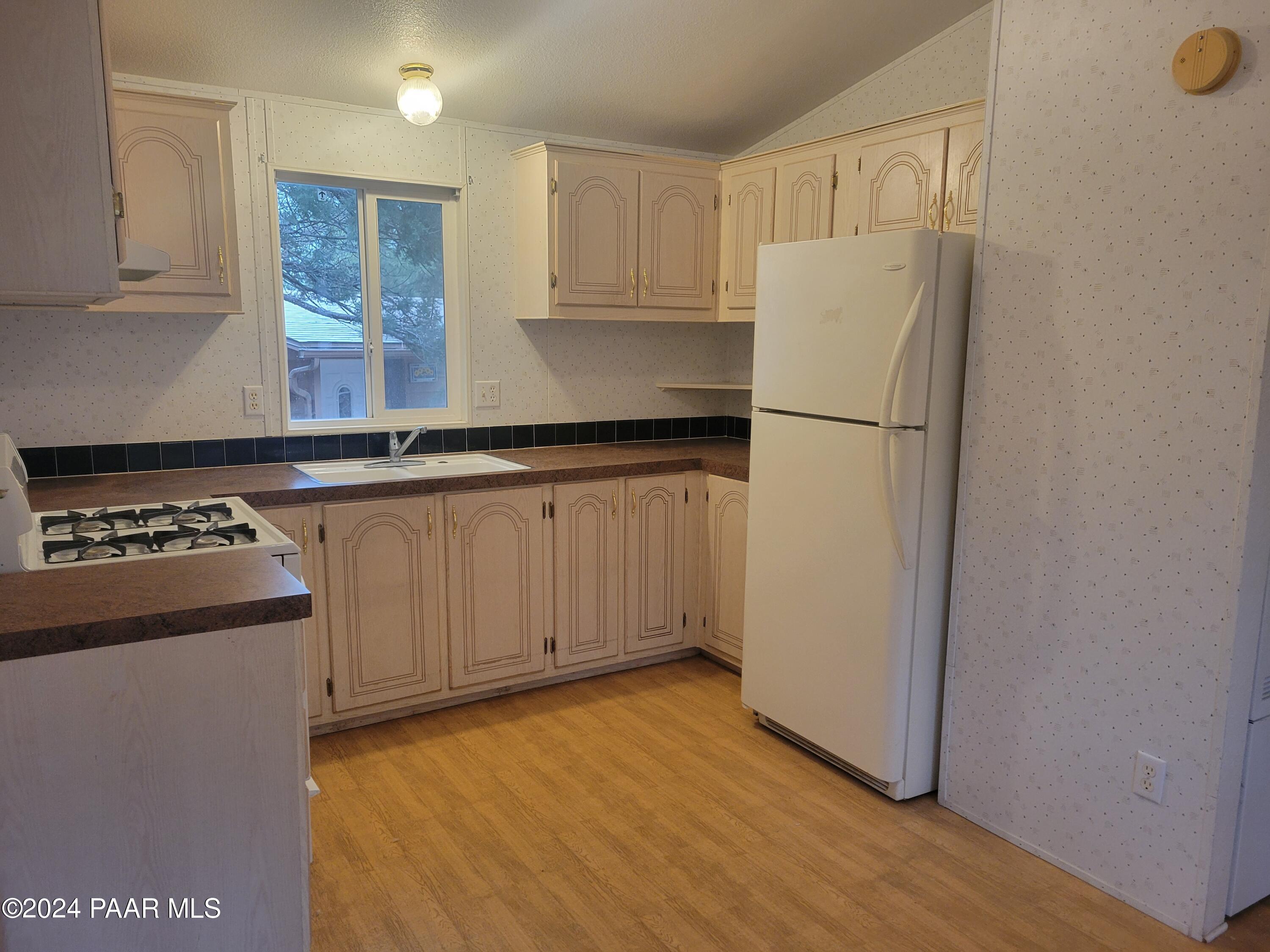 99 Alpine Prescott, AZ 86305 - Photo 7 of 25 a kitchen with granite countertop a refrigerator a sink and white cabinets